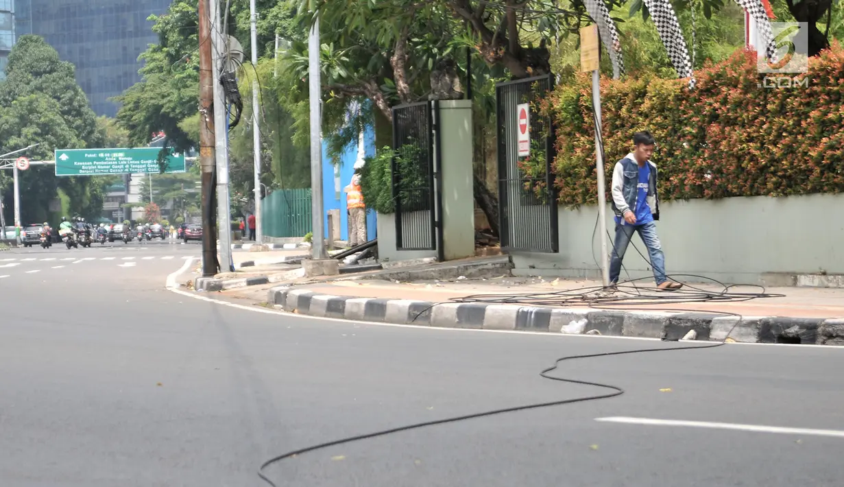 Pejalan kaki melintasi kabel listrik yang menjuntai di Jalan Haji Agus Salim, Jakarta, Minggu (9/9). Instalasi kabel yang menjuntai ke jalan akibat tersangkut truk itu dapat membahayakan warga dan pengendara yang melintas (Merdeka.com/ Iqbal S. Nugroho)
