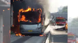Petugas tengah berusaha memadamkan api yang membakar badan bus Transjakarta di kawasan Salemba, Jakarta, Jumat (3/7/2015). Kobaran api tampak membakar bus gandeng berwarna abu-abu itu, bahkan api juga menyambar bagian halte. (twitter.com/PT_TransJakarta)