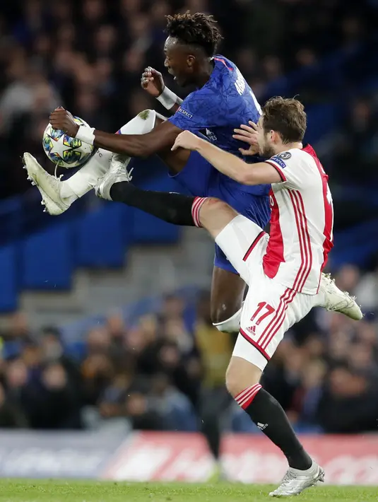 Penyerang Chelsea, Tammy Abraham berebut bola dengan bek Ajax, Daley Blind  pada pertandingan lanjutan Grup H Liga Champions di Stamford Bridge, London (5/11/2019). Chelsea bermain imbang 4-4 atas Ajax. (AP Photo/Frank Augstein)