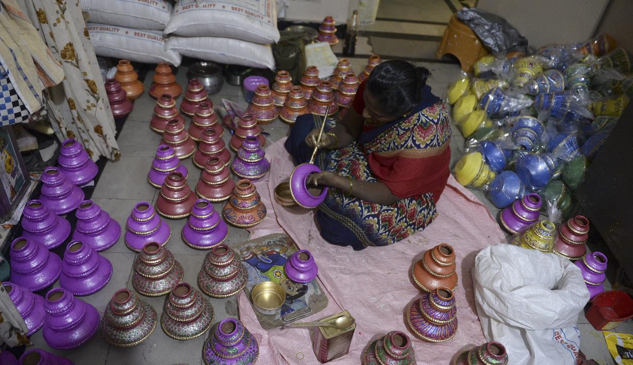 Perajin mewarnai pot minyak tembikar atau diyas menjelang Diwali, festival lampu Hindu, di Hyderabad (4/11/2020). Selama perayaan Diwali, para warga melakukan ritual pembersihan, mulai dari membersihkan dan menghias rumah, berkumpul untuk pesta-pesta khusus. (AFP Photo/Noah Seelam)