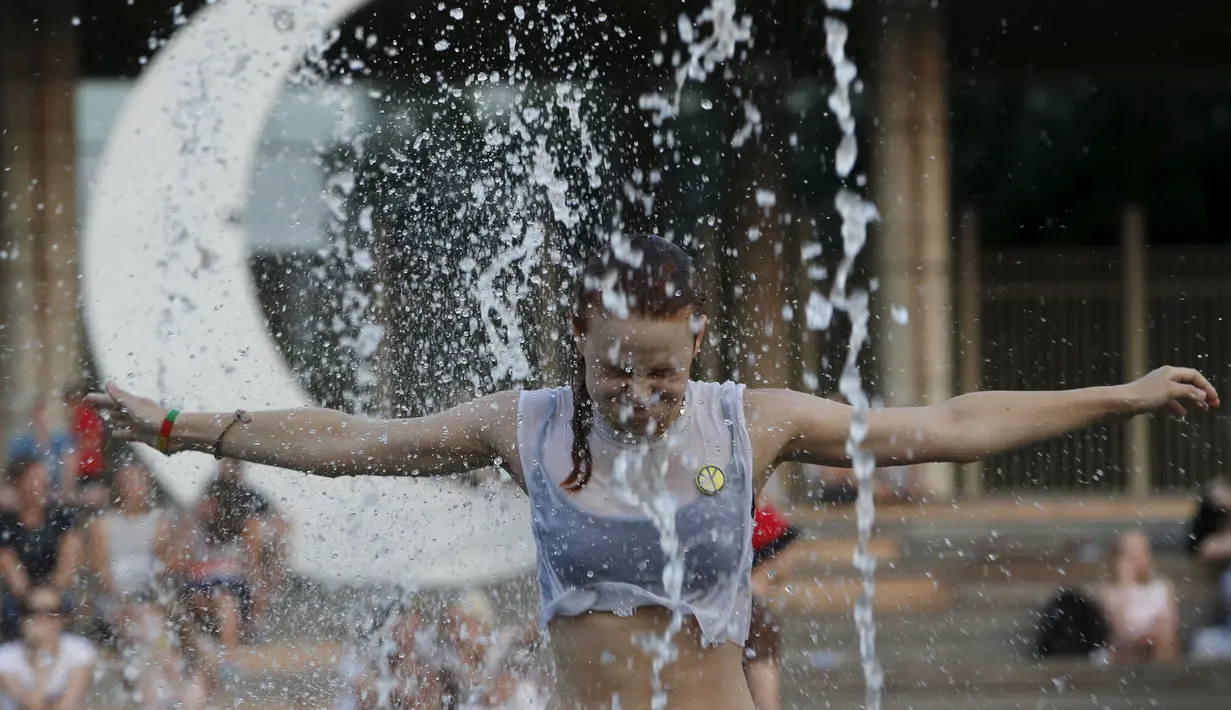 Seorang wanita menikmati bermain diantara air mancur saat menikmati musim panas di taman Gorky, Moskow, Rusia, Minggu (9/8/2015). (REUTERS/Sergei Karpukhin)