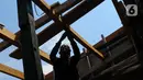 Tukang kayu memperbaiki kapal motor di Pelabuhan Kalibaru, Jakarta, Rabu (8/3/2023). Tukang kayu mengalami kesulitan bahan baku yang mulai jarang. (merdeka.com/Imam Buhori)