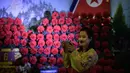 Seorang wanita menggunakan ponsel untuk mengambil gambar selama pameran bunga 'Kimjongilia' di Pyongyang, Kamis (14/2). Korea Utara menggelar festival bunga untuk merayakan ulang tahun mendiang ayah Kim Jong-un, Kim Jong-il. (Ed JONES/AFP)