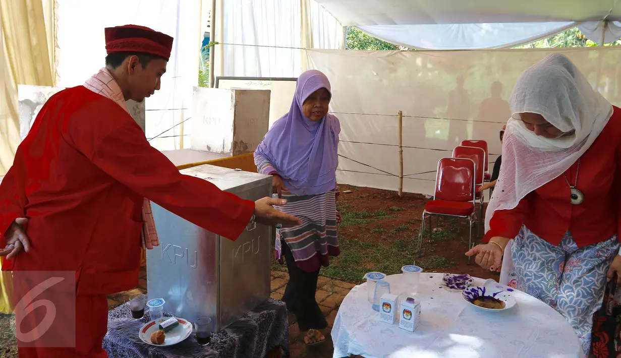 Petugas KPPS mengenakan pakaian ala Betawi mempersilahkan  pemilih untuk mencelupkan jarinya ke tinta di TPS 31/32, Kelurahan Pondok Benda, Tangerang Selatan, Rabu (9/12). Pilkada Kota Tangsel ini diikuti tiga pasangan calon. (Liputan6.com/Fery Pradolo)