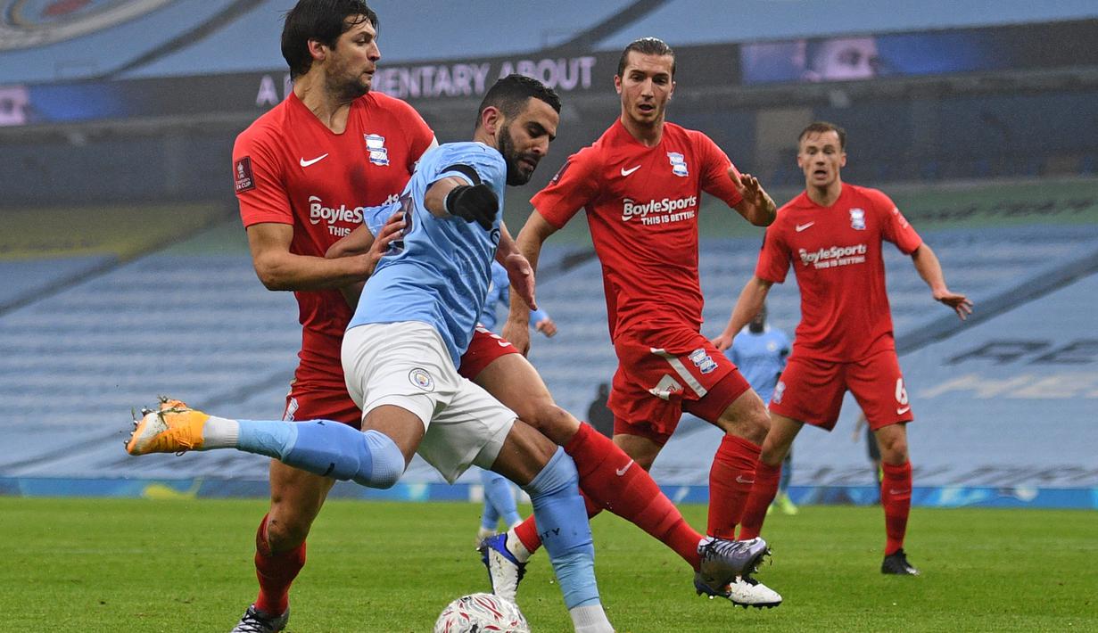 Gelandang Manchester City, Riyad Mahrez (tengah) melepaskan umpan dibawah tekanan pemain Birmingham City dalam laga babak ke-3 Piala FA 2020/21 di Etihad Stadium, Minggu (10/1/2021). Manchester City menang 3-0 atas Birmingham City. (AFP/Oli Scarff/Pool)