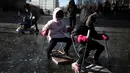 Sejumlah anak bermain di sungai yang membeku di Beijing, China (21/1). Akibat membeku, Sungai ini menjadi objek wisata dadakan yang banyak diminati wisatawan. (AFP/Fred Dufour)