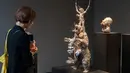 Seorang wanita melihat patung yang berjudul "Demon with Bowl" karya seniman Inggris, Damien Hirst saat pameran di Venice, Italia (6/4). Karya itu sebelumnya direndam dalam laut hingga teroksidasi dan menimbulkan lapisan karang. (AFP Photo/Miguel Medina)
