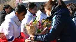 Tim Korea Selatan (kanan) memberi bunga kepada tim hoki es Korea Utara saat tiba di pusat pelatihan nasional Jincheon, Korsel (25/1). (AFP Photo/Pool/ Kyung-Seok)