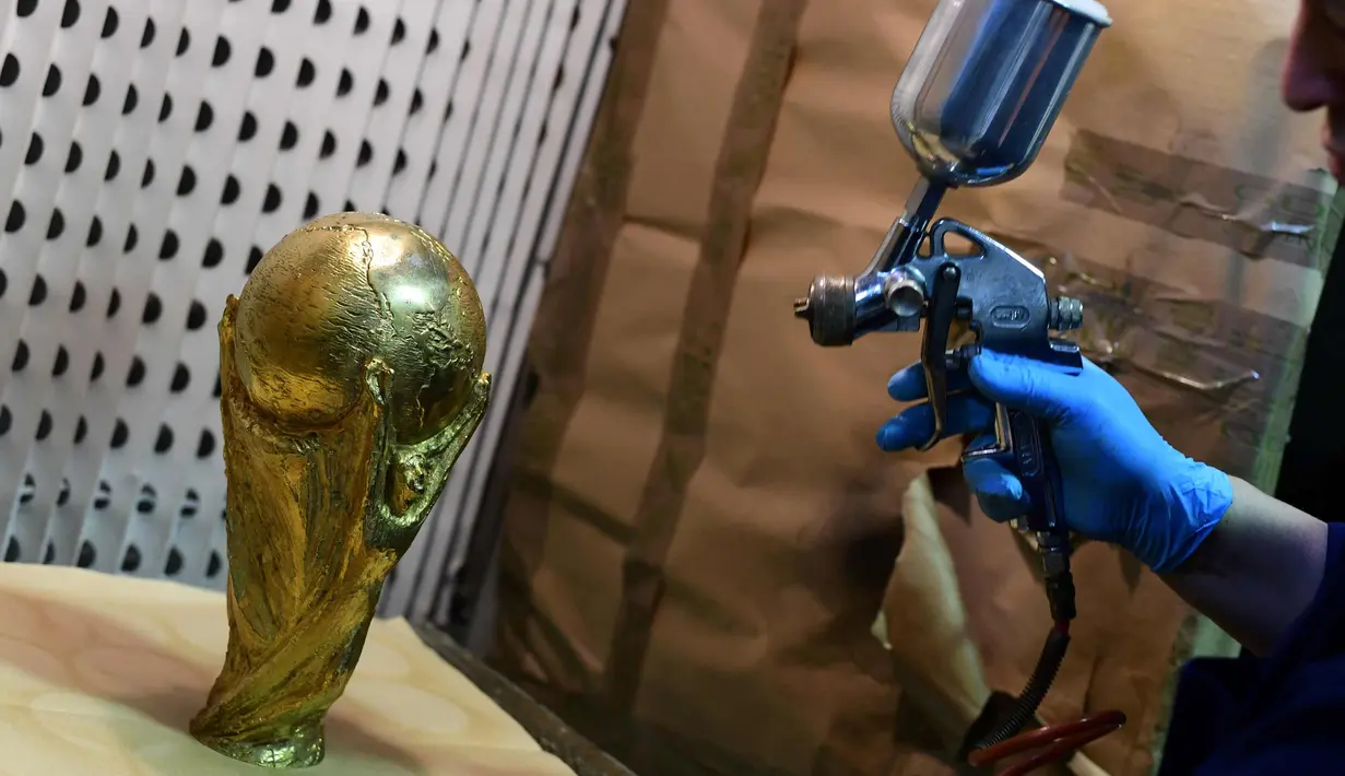 Pekerja menyemprotkan cat ke replika trofi Piala Dunia FIFA di piala Italia dan pabrikan medali GDE Bertoni di Paderno Dugnano, Milan (11/4). Piala Dunia akan diselenggarakan 14 Juni sampai 15 Juli di Rusia. (AFP Photo/Miguel Medina)