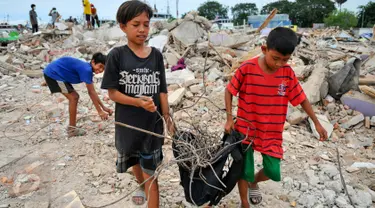 Dua orang anak membawa sisa-sisa besi dari reruntuhan bangunan yang dirobohkan di kawasan Pasar Ikan, Penjaringan, Jakarta, Selasa (12/4). Selain warga, sejumlah pemulung besi berhambur untuk menjarah besi dari bekas bangunan (Liputan6.com/Yoppy Renato)