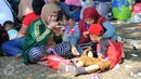 Meski hanya beralaskan tikar diatas rumput, namun kecerian dan kekeluargaan sangat terasa saat makan bersama di area wisata Taman Mini Indonesia Indah, Jakarta, Minggu (19/07/2015). (Liputan6.com/Yoppy Renato)
