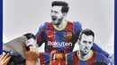 Pekerja melepas poster yang menampilkan pemain depan Argentina, Lionel Messi di pintu masuk Stadion Camp Nou, Barcelona pada Selasa, 10 Agustus 2021. Lionel Messi resmi meninggalkan Barcelona akibat masalah finansial klub dan peraturan dari Liga Spanyol. (AFP/Pau Barrena)