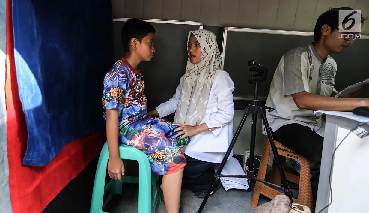 Petugas Disdukcapil melakukan pengarahan kepada anak untuk pemotretan Kartu Identitas Anak (KIA) di Pondok Aren, Tangerang Selatan, Jumat (16/11). KIA mirip dengan data yang tertera di dalam KTP. (Liputan6.com/Fery Pradolo)