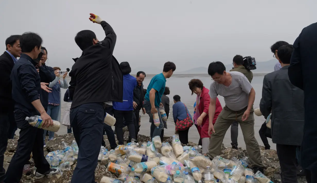 Aktivis pembelot Korea Utara melemparkan botol berisi beras, uang dan USB  ke laut dari pulau Ganghwa, barat Seoul, Selasa (1/5). Mereka telah melempar ratusan botol informasi tersebut dua kali sebulan selama lebih dari dua tahun terakhir. (AFP/ED JONES)