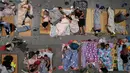 Warga beristirahat di ruang pameran setelah dievakuasi di Hangzhou di provinsi Zhejiang, China timur (25/7/2021). Ratusan orang telah dievakuasi dari daerah pesisir kota Shanghai, China saat Topan In-Fa menghantam pantai di wilayah selatan, Selasa (27/7). (Chinatopix via AP)