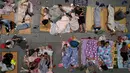 Warga beristirahat di ruang pameran setelah dievakuasi di Hangzhou di provinsi Zhejiang, China timur (25/7/2021). Ratusan orang telah dievakuasi dari daerah pesisir kota Shanghai, China saat Topan In-Fa menghantam pantai di wilayah selatan, Selasa (27/7). (Chinatopix via AP)