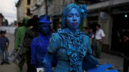 Kontestan berjalan saat  mengikuti kontes patung di pusat kota San Salvador , El Salvador, (18/6). Dengan mengecat seluruh tubuh mereka seperti patung, kita akan dibuat sulit membedakan mana patung asli dan tidak. (REUTERS / Jose Cabezas)