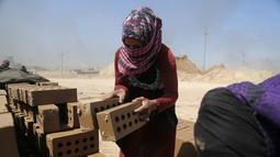 Zahra Ali (19) bekerja di pabrik batu bata di sebuah pabrik batu bata di pinggiran tenggara Baghdad Nahrawan, Irak, Kamis (24/5/2021). Ali bekerja 12 jam sehari dengan upah sekitar USD$ 15. (AP Photo/Hadi Mizban )