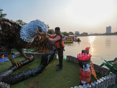 Petugas Pasukan Oranye DLH DKI Jakarta menyelesaikan pembuatan perahu berbahan botol plastik bekas di kawasan Danau Sunter Selatan, Jakarta Utara. Sebanyak 43 perahu dengan beragam desain unik disiapkan untuk meramaikan CiLung Fest 2026, Selasa (13/10/2026).(KLY/Budy Santoso)
