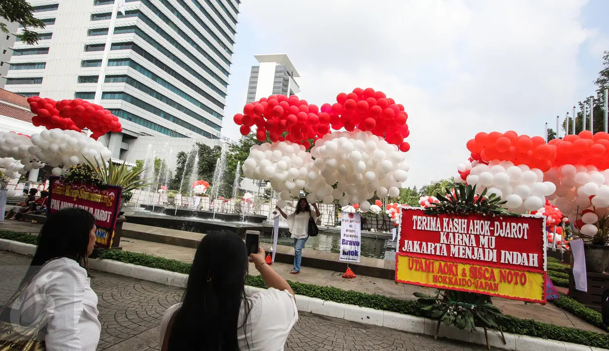 Warga berswafoto dengan balon merah putih yang menghiasi halaman Balai Kota DKI Jakarta, Senin (8/5). Balon-balon tersebut merupakan bentuk dukungan moril untuk Basuki T Purnama atau Ahok yang akan menjalani sidang putusan. (Liputan6.com/Faizal Fanani)