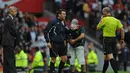Manchester United vs Arsenal. (29/8/2009). Wasit Mike Dean (kanan) menghampiri manajer tim Arsenal, Arsene Wenger untuk memberi kartu merah dan mengusirnya ke tribun usai mendapat masukan dari ofisial keempat, Lee Probert. (AFP/Paul Ellis)