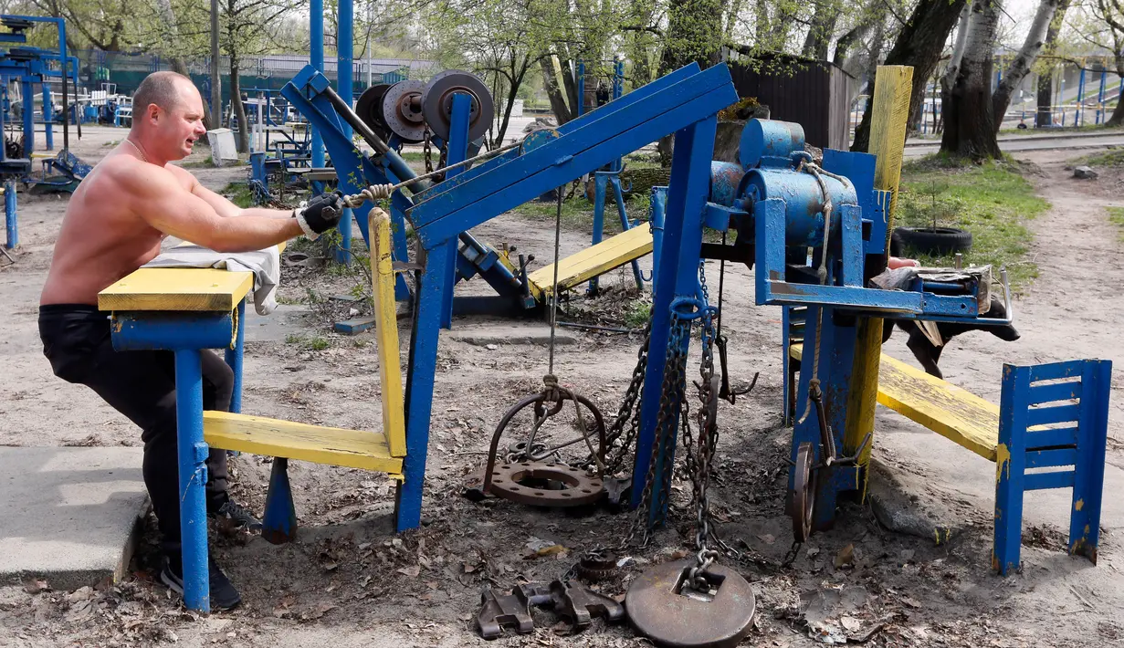 Seorang pria berlatih menarik beban di outdoor gym atau pusat kebugaran terbuka di tepi Sungai Dnipro, Kiev, Ukraina, Kamis (18/4). Pusat kebugaran ini memanfaatkan besi tua bekas kendaraan sebagai alat fitness. (AP Photo/Efrem Lukatsky)