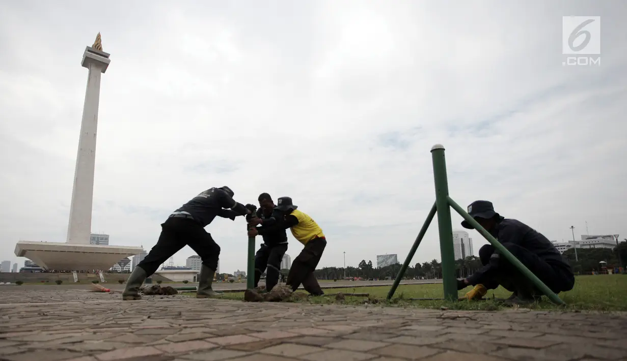 Petugas Unit Pengelola Kawasan (UPK) Monas mencopot pagar pembatas antara jalan dengan taman di kawasan Monas, Jakarta, Jumat (11/1). Pencabutan pagar itu merupakan arahan langsung dari Wakil Gubernur DKI Sandiaga Uno. (Liputan6.com/Arya Manggala)