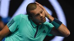 Ekspresi petenis putra Prancis, France's Jo-Wilfried Tsonga, saat peregangan otot jelang melawan petenis Jepang, Kei Nishikori, di turnamen tenis Australia Terbuka 2016 di Melbourne Park, Australia, (24/1/2016). (AFP/Greg Wood)