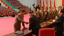 Pemimpin Korea Utara Kim Jong-un berjabat tangan saat memberi penghargaan kepada para ilmuwan di bidang pertahanan nasional Korea Utara di Pyongyang (12/12). (AFP Photo/KCNA VIA KNS)