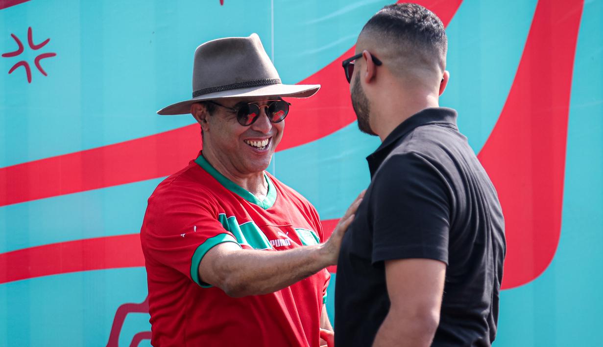 <p>Suporter Maroko, Mohammad Aziz Mrabat (kiri) ditemui oleh salah satu ofisial Timnas Maroko U-17 menjelang laga kedua Grup A Piala Dunia U-17 2023 melawan Timnas Ekuador U-17 di Stadion Gelora Bung Tomo (GBT), Surabaya, Senin (14/11/2023). (Bola.com/Bagaskara Lazuardi)</p>
