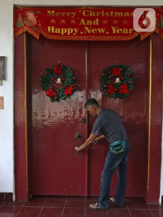 Pekerja menghias pintu Gereja Tugu dengan ornamen Natal, Jakarta, Senin (23/12/2019). Sejumlah perlengkapan ibadah telah disiapkan untuk menyambut Natal. (Liputan6.com/Herman Zakharia)