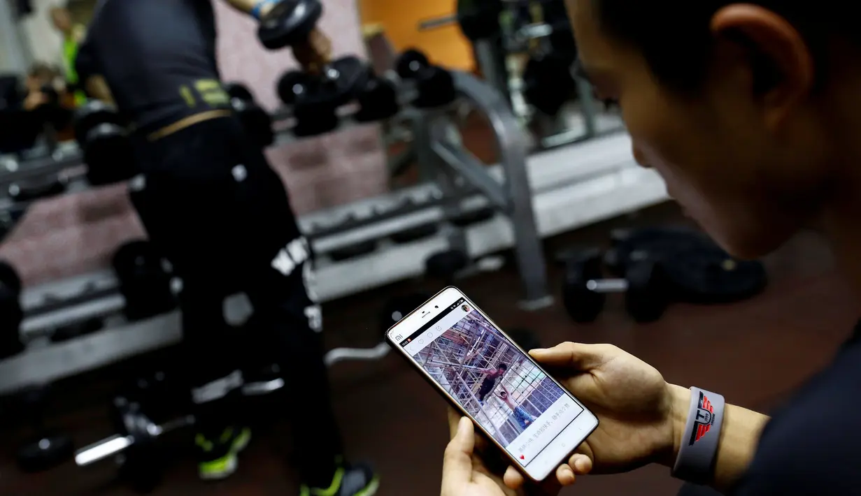 Pelatih kebugaran Bi Zhenbo melihat video atraksi Shi Shenwei, Fujian, Cina (28/9). Menurut Bi Zhenbo aksi Shi menakjubkan dan menginspirasi banyak anak muda di Cina. (REUTERS/ Thomas Peter)