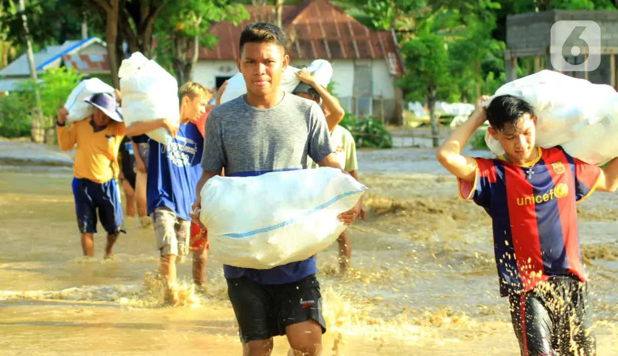 Warga membawa barang miliknya saat banjir bandang  di Kabupaten Bone Bolango, Gorontalo (11/6/2020). Data sementara yang diterima dari BPBD Kabupaten Bone Bolango sekitar 1.078 kepala keluarga serta 5.407 jiwa terdampak banjir bandang. (Liputan.com/Arfandi Ibrahim)