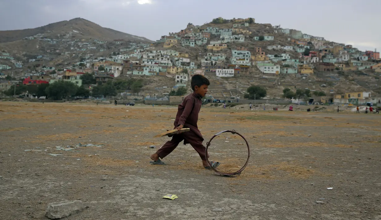 Seorang bocah Afghanistan mendorong roda saat terjadi badai pasir di pinggiran Kabul, Afghanistan (25/8/2020). Sebuah badai pasir hebat melanda Kabul. Badai menyebabkan jarak pandang jadi berkurang. (AP Photo / Rahmat Gul)
