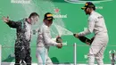 Pembalap tim Mercedes, Lewis Hamilton dan Nico Rosberg menyemprotkan sampanye ke arah direktur teknis Mercedes, Paddy Lowe saat merayakan kemenangan di balapan F1 Grand Prix Meksiko, Meksiko (30/10). (Reuters/Henry Romero)