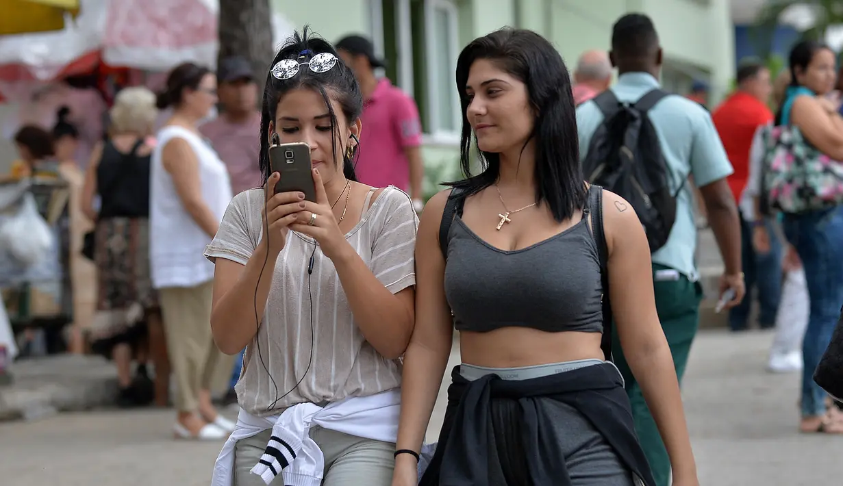 Seorang wanita menggunakan ponselnya untuk terhubung ke internet melalui WiFi di Havana, Rabu (5/12). Kuba merupakan salah satu negara terakhir di dunia yang masih belum menerapkan internet mobil. (YAMIL LAGE/AFP)