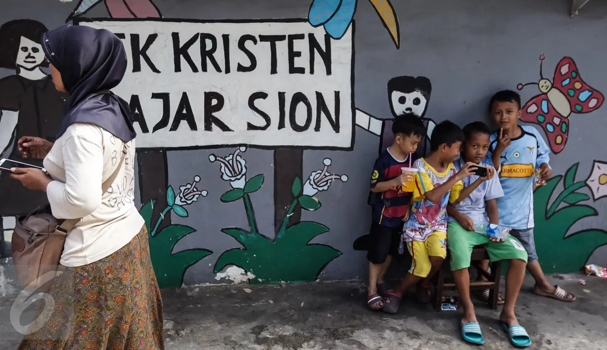 Seorang ibu yang sedang melintas dan anak-anak tengah duduk di taman bermain TK Kristen Fajar Sion, Jakarta Barat, Minggu (8/1). Guna mengurangi trauma kebakaran, mereka memanfaatkan taman bermain di sekolah tersebut. (Liputan6.com/Fery Pradolo)