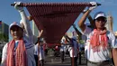 Warga Kamboja membentangkan syal krama untuk memecahkan rekor Guinness sebagai syal tenun terpanjang dunia di Phnom Penh, Minggu (1/7). Syal dengan panjang 1.149,8 meter dan lebar 88 cm tersebut dibentangkan di luar Istana Kerajaan. (AFP/TANG CHHIN Sothy)