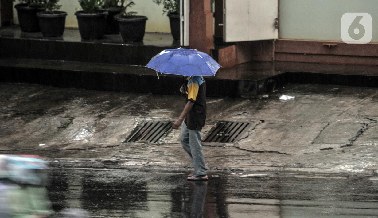 Pejalan kaki menggunakan payung saat hujan mengguyur Jakarta, Senin (26/10/2020). BPBD DKI Jakarta mengeluarkan peringatan dini cuaca berupa potensi terjadinya hujan lebat disertai petir dan angin kencang dampak dari siklon tropis Molave hingga 27 Oktober 2020. (merdeka.com/Iqbal S. Nugroho)
