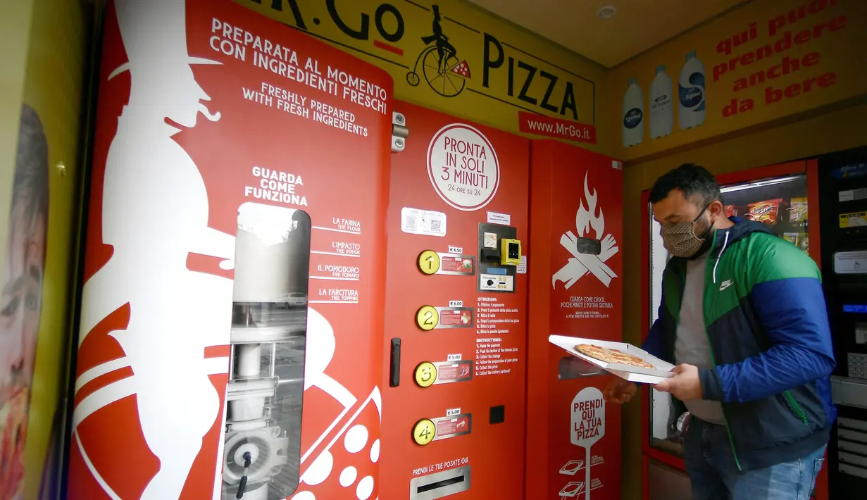 Seorang pria mengambil pesanannya di mesin penjual pizza otomatis, yang pertama dari jenisnya di pusat kota Roma, pada 29 April 2021. Mesin penjual otomatis ini mampu menguleni adonan, membumbui, memasak, dan menyajikan pizza dalam kotak karton hanya dalam waktu tiga menit. (Filippo MONTEFORTE/AFP)