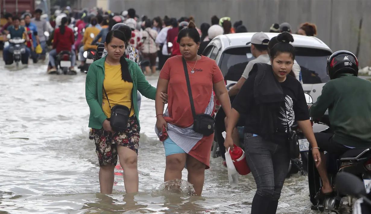 Pekerja garmen pergi ke tempat kerja melalui jalan yang banjir setelah hujan di  Phnom Penh, Kamboja (14 /10/2020). Pejabat bencana Kamboja mengatakan bahwa lebih dari 10.000 orang telah dievakuasi ke tempat aman setelah badai tropis melanda yang menyebabkan banjir bandang.  (AP Photo/Heng Sinith)