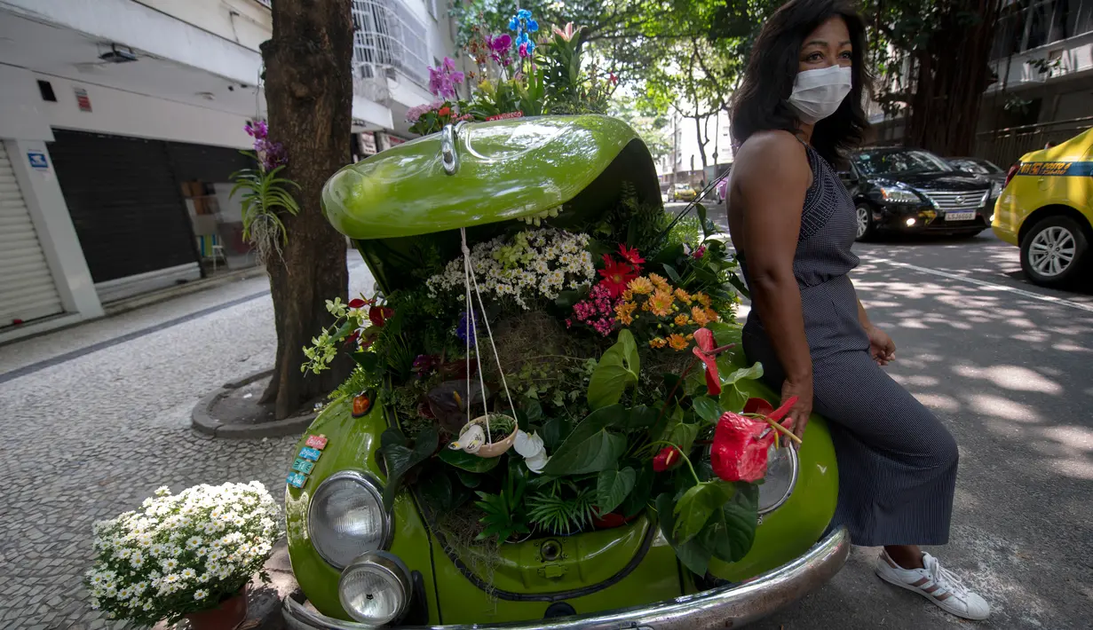 Roberta Machado dari Brasil berpose dengan Volkswagen Beetle 1969 miliknya yang diubah menjadi toko bunga keliling di Copacabana, Rio de Janeiro, Rabu (14/10/2020). Perempuan 51 tahun ini mengubah VW kodok untuk bertahan dari krisis akibat pandemi COVID-19. (MAURO PIMENTEL/AFP)