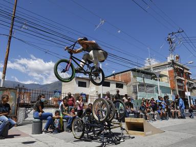 Pebalap BMX Leudar Ruiz melakukan aksi dalam sebuah pertunjukan yang menandai peringatan 400 tahun permukiman kumuh Petare di Caracas, Venezuela (17/2/2021). Petare yang merupakan kawasan kumuh terbesar di Venezuela menjadi rumah bagi lebih dari 500.000 jiwa. (AP Photo/Ariana Cubillos)