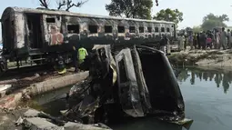 Sebuah truk hangus terbakar usai kecelakaan antara kereta penumpang dan kereta tangki minyak di Distrik Sheikhupura, Punjab, Selasa (28/3). Akibat kejadian tersebut sejumlah gerbong kereta dan kendaraan hangus terbakar. (AFP Photo / Ludovic Marin)