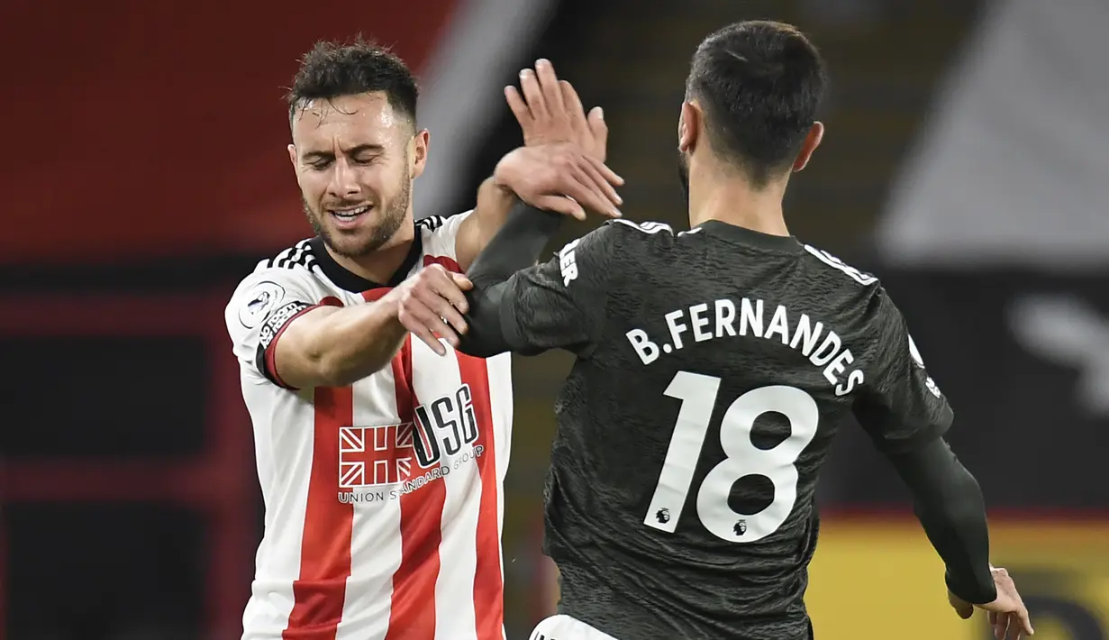 Gelandang Manchester United, Bruno Fernandes (kanan), terlibar pertikaian dengan bek Sheffield United, George Baldock, dalam laga lanjutan Liga Inggris pekan ke-13 di Bramall Lane, Sheffield, Kamis (17/12/2020). Manchester United menang 3-2 atas Sheffield United. (AFP/Peter Powell/Pool)