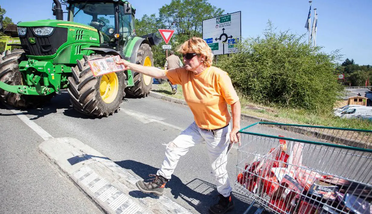 Petani membagikan produk yang diambil dari supermarket Casino kepada pengendara yang lewat di Sarlat, Perancis barat daya, sebagai bentuk demo di supermarket tersebut, Kamis (20/8/2015). (AFP PHOTO/Yohan Bonnet)