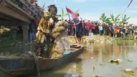 Aksi teatrikal seorang perempuan naik perahu dan mengambil sampah yang ada di sungai mewarnai upacara pengibaran bendera HUT RI di pegunungan Kendeng. (Liputan6.com/ Arief Pramono)