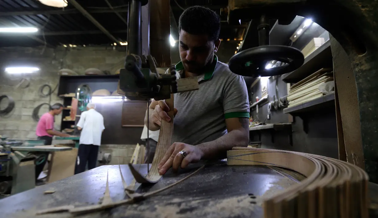 Pekerja memotong kayu untuk pembuatan alat musik Oud di sebuah rumah produksi di Damaskus, Suriah (17/7). Oud sering juga disebut Gitar Gambus yang bentuknya sepeti buah pir. (AFP Photo/Louai Beshara)