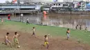 Anak-anak bermain sepak bola di bantaran Kanal Banjir Barat, Jakarta, Jumat (5/4). Tidak adanya lapangan menjadikan lokasi tersebut sebagai tempat bermain mereka, meskipun dalam kondisi seadanya. (Liputan6.com/Immanuel Antonius)