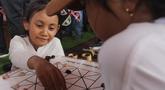 Anak-anak mencoba permainan tradisional di acara Teras Main Indonesia 2025 di Taman Mini Indonesia Indah (TMII), Jakarta, Sabtu (15/11/2025). Sebagai upaya pelestarian budaya, Komite Permainan Rakyat dan Olahraga Tradisional Indonesia (KPOTI) menggelar festival permainan tradisional bertajuk Teras Main Indonesia 2025. (merdeka.com/Arie Basuki)